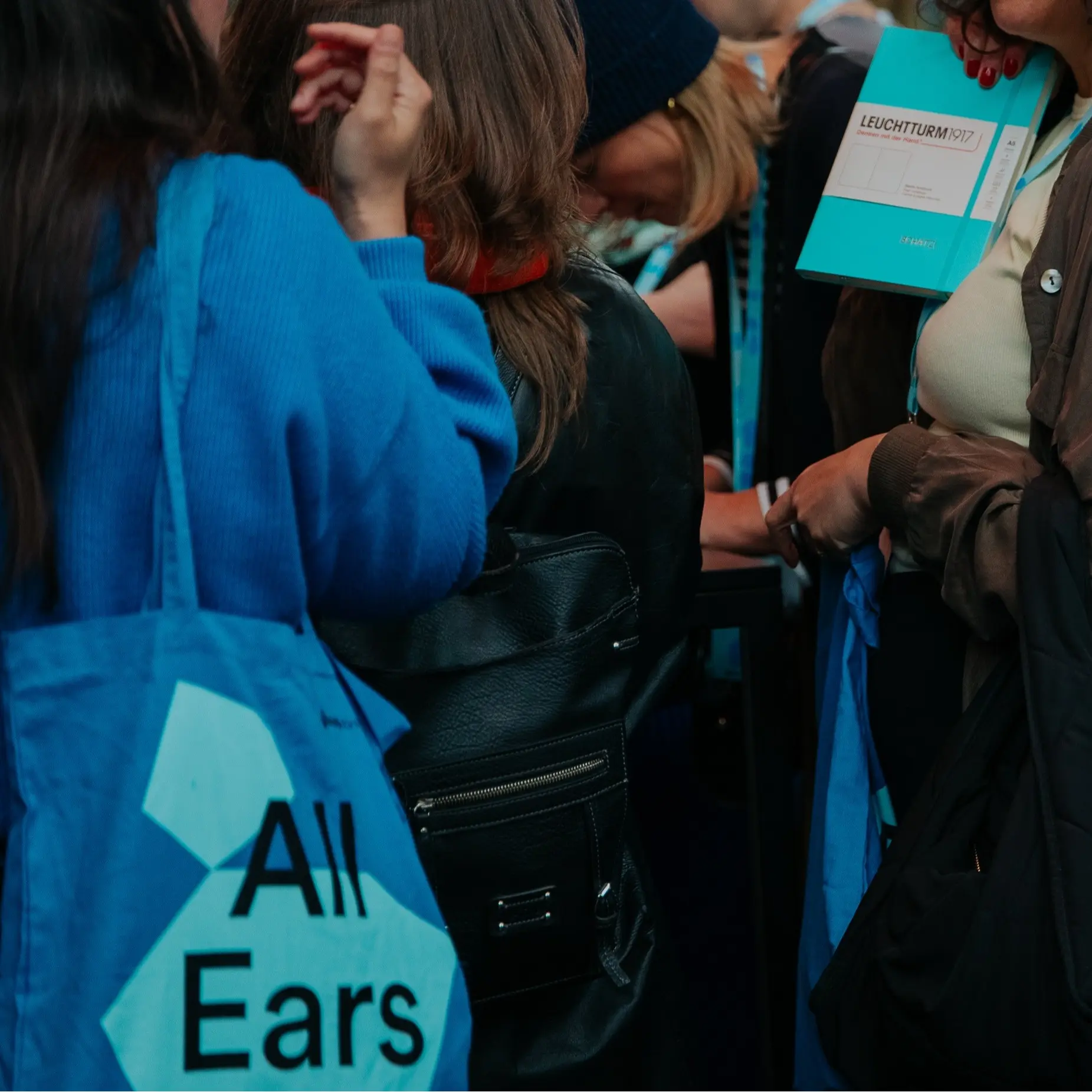 Visitantes esperan en el stand, sostienen libretas seleccionadas y observan el proceso de grabado.